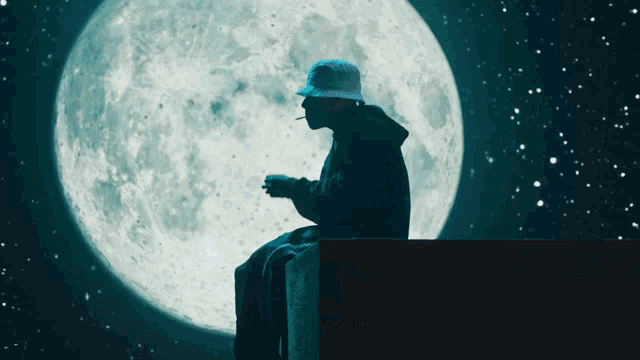 a man smoking a cigarette while sitting in front of a full moon