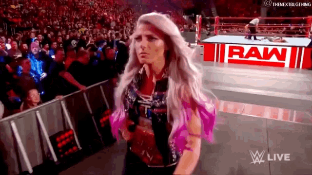 a woman is holding a microphone in front of a raw sign .