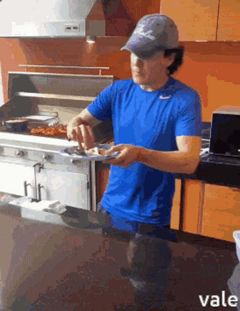 a man wearing a blue nike shirt is holding a plate of food