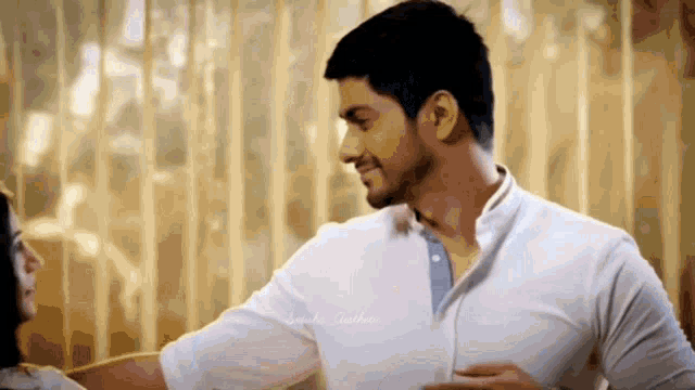 a man in a white shirt is smiling and looking at another man