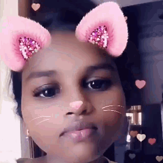 a little girl wearing pink cat ears and a nose .