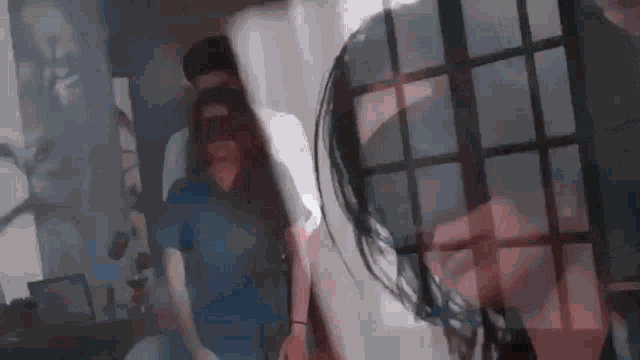 a man and a woman are standing next to each other in a room . the woman is wearing a blindfold .