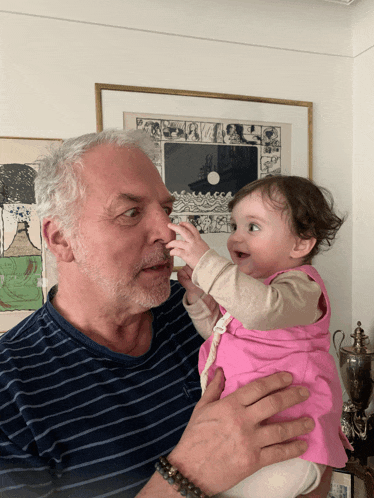 a man is holding a baby in his arms and the baby is licking his nose