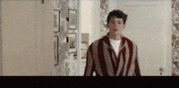 a man in a striped jacket is standing in a hallway .