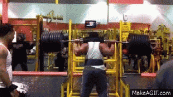 a man squatting with a barbell in a gym with makeagif.com on the bottom right