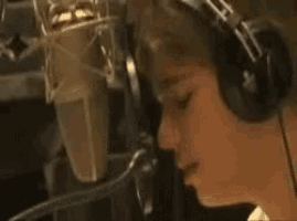 a man wearing headphones is singing into a microphone in a studio .