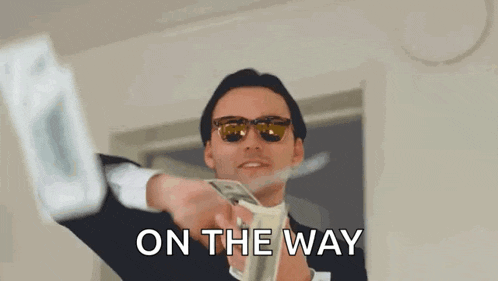 a man in a suit and sunglasses is throwing money in the air and the words on the way are behind him .