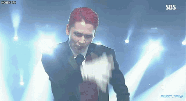 a man in a suit and tie is dancing on a stage with sbs written on the bottom