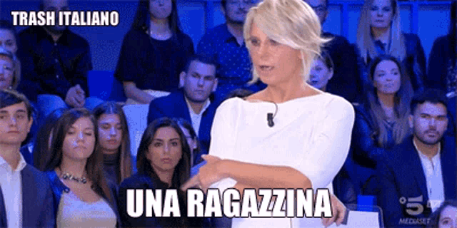 a woman is standing in front of a crowd and says una ragazzina .