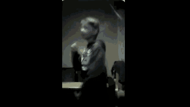 a blurry picture of a man standing in front of a table in a dark room .