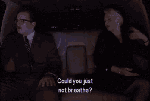 a man and woman are sitting in a car and the woman is asking the man if he could just not breathe