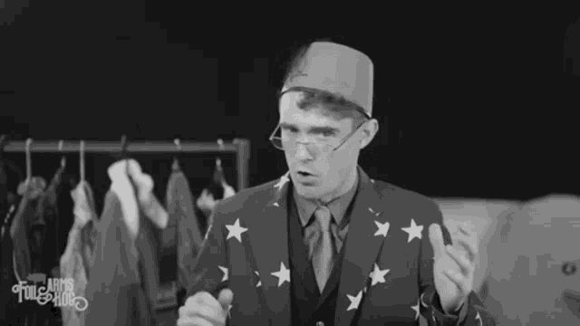 a man in a suit with stars on it is standing in front of a rack of clothes