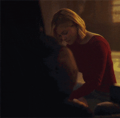 a woman in a red sweater is sitting on the ground with a bag