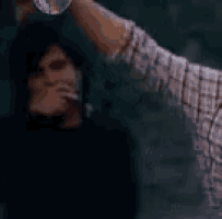 a man in a plaid shirt is holding a globe over a woman in a black shirt .