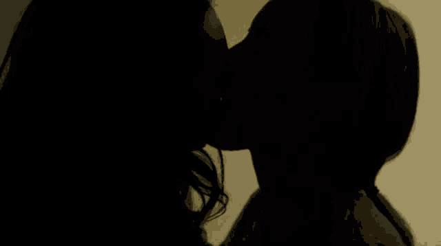 a man and woman are kissing in a dark room