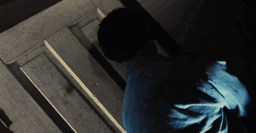 a man in a blue shirt is standing in a dark room