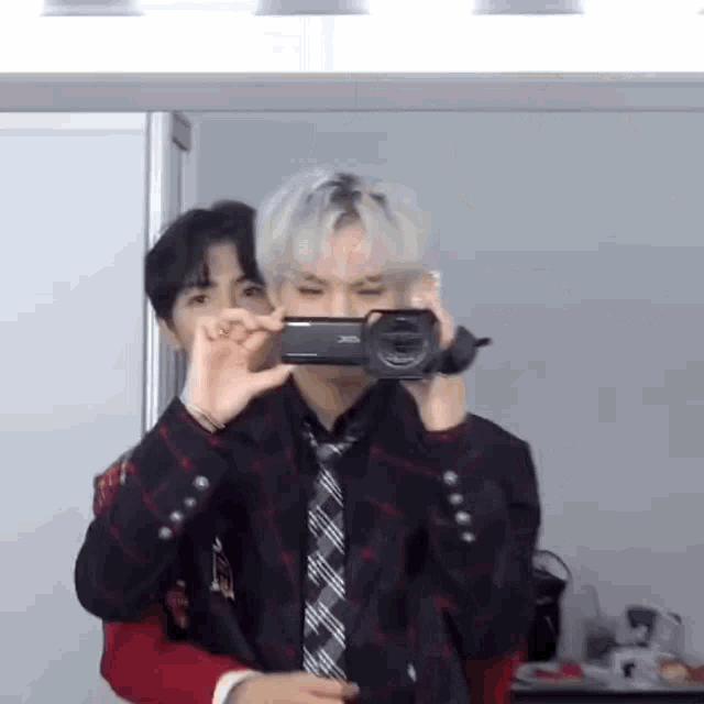 a man is taking a picture of another man with a camera in front of a mirror .