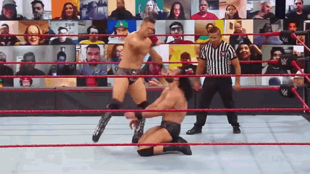 two men are wrestling in a wrestling ring with a referee watching .