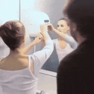 a woman looks at her reflection in a mirror