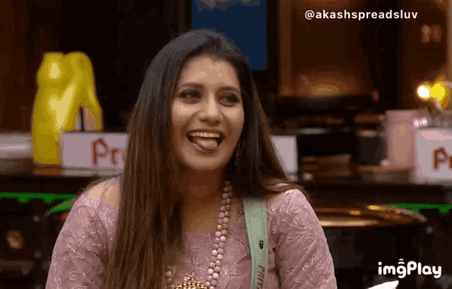 a woman in a pink dress is laughing with her tongue hanging out .