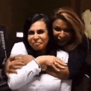 two women are hugging each other in a room and smiling for the camera .