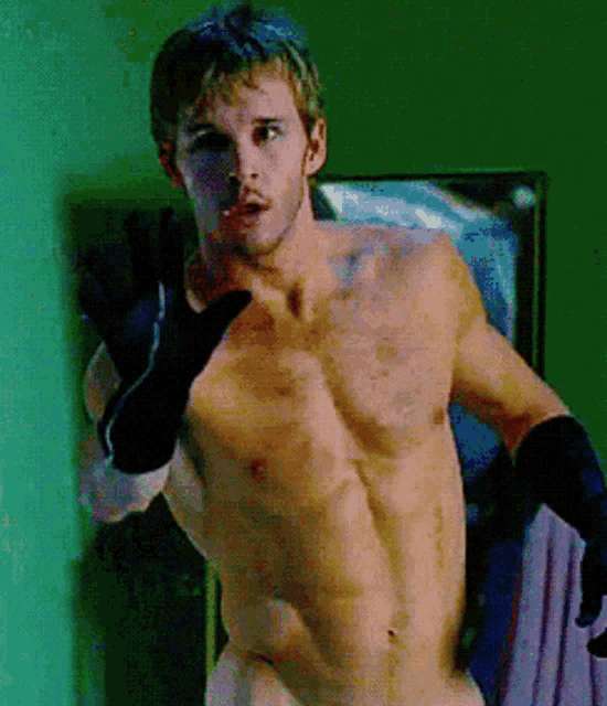 a shirtless man wearing black boxing gloves