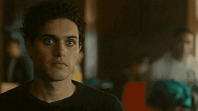 a close up of a man 's face with curly hair looking at the camera .