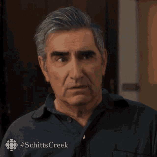 a close up of a man 's face with #schittscreek written on the bottom
