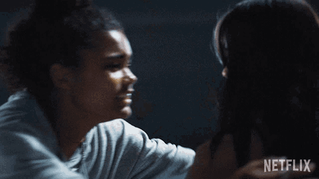 a woman is hugging another woman in a dark room .