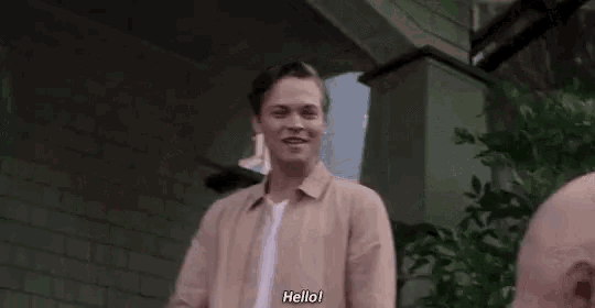 a young man is waving his hand in front of a building and another man .