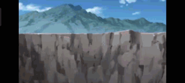 a rock wall with mountains in the background