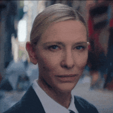 a woman in a suit and tie looks at the camera with a serious look on her face