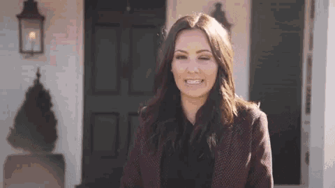 a woman is smiling and standing in front of a house .