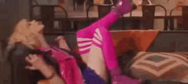 two women are laying on top of each other on a couch in a living room .