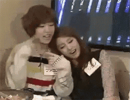 two women are sitting next to each other in front of a tv .