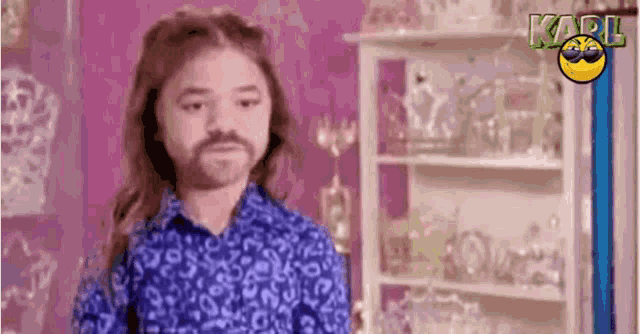 a girl with long hair and a beard is standing in front of a shelf .