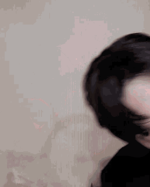 a close up of a person 's face with their hair blowing in the wind against a white wall .