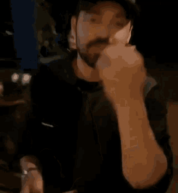 a man wearing a hat is sitting at a table eating a sandwich .