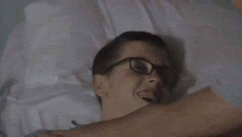 a man is sitting on a couch with his head in his hands in a dark room .