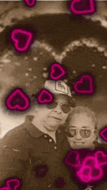 a man and a woman are posing for a photo with pink hearts surrounding them