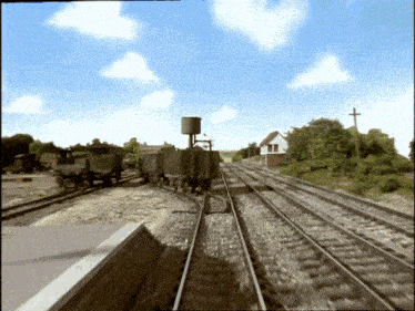 a train going down the tracks with a water tower in the foreground