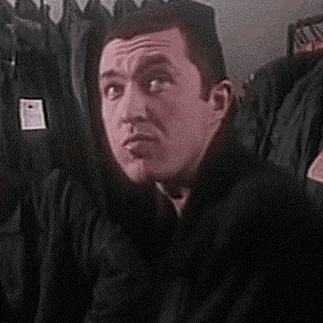 a man is making a surprised face while sitting in a chair .