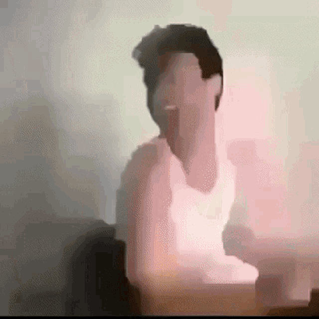 a man in a white tank top is sitting in front of a pink light .
