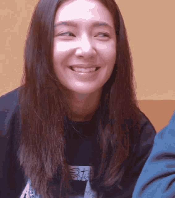 a woman with long hair is smiling and wearing a black shirt