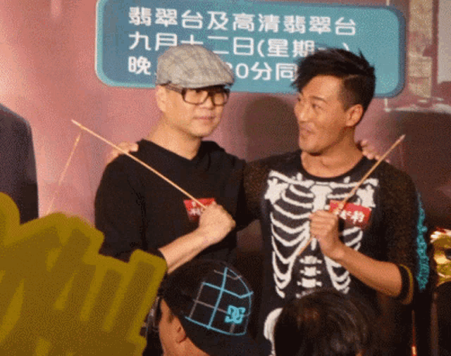 two men are posing for a picture in front of a sign with chinese writing on it