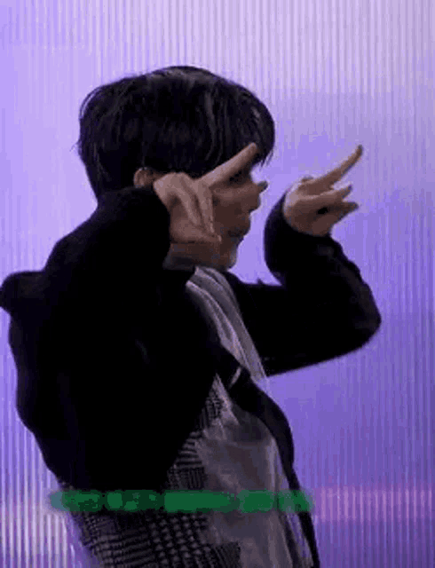 a man in a black jacket is making a peace sign with his hands .