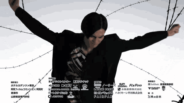 a man with his arms outstretched in front of barbed wire and a list of sponsors