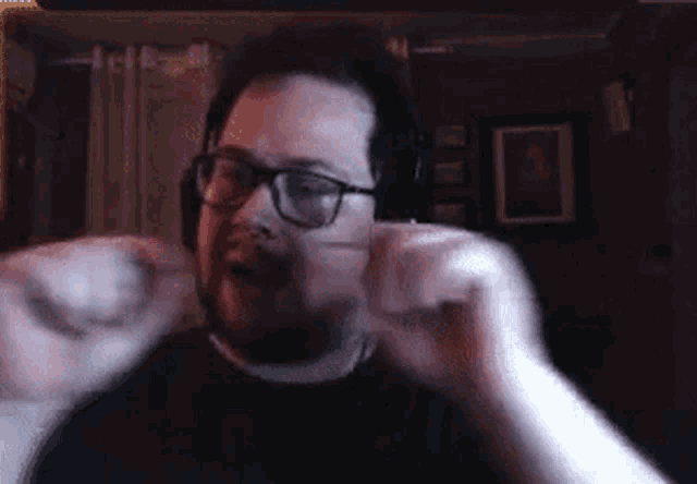 a man with glasses and a beard is wearing headphones and making a funny face .