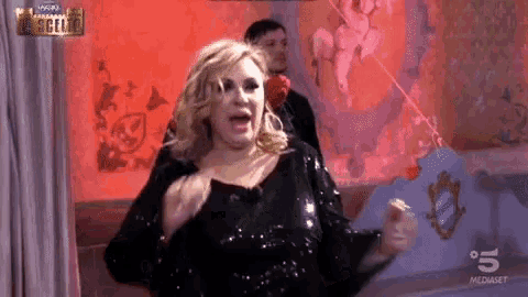 a woman in a black sequined dress is dancing in front of a wall that says ' scelle ' on it