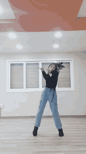 a woman is dancing in a room with a window